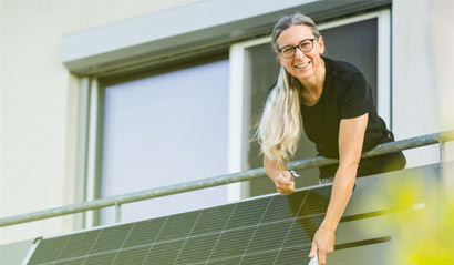 Frau auf Balkon reinigt Solarpanel